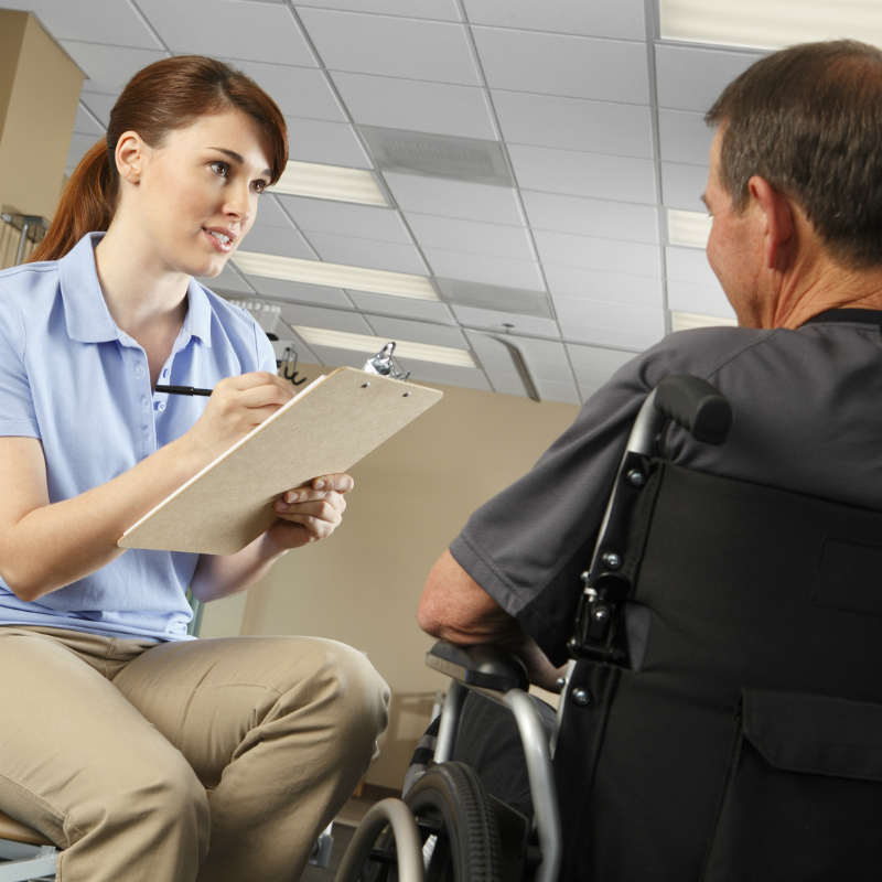 Health worker speaking to man in wheelchair